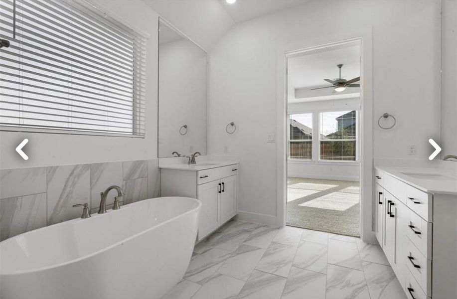 Full bathroom featuring two vanities, light marble finish flooring, a freestanding tub, recessed lighting, and ceiling fan