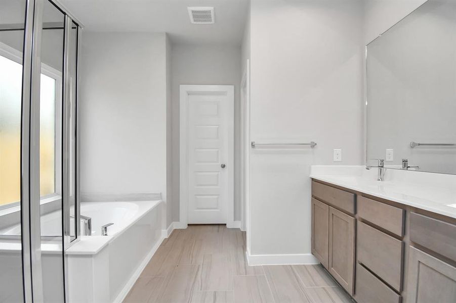 Indulge in a spa-like retreat within the confines of this primary bathroom. Photo shown is example of completed home with similar plan. Photo shown is example of completed home with similar plan. Actual colors and selections may vary.