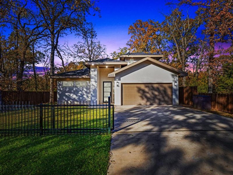 View of front facade featuring driveway, stucco siding, and a garage