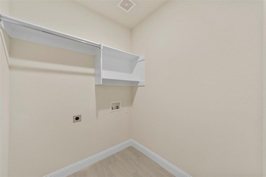 Clothes washing area featuring hookup for an electric dryer, hardwood / wood-style flooring, and washer hookup