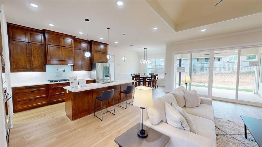 Kitchen featuring, light wood finished floors, light countertops, gas cooktop, and a kitchen bar