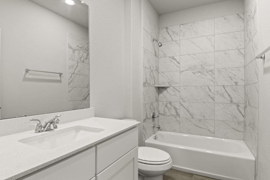 Image of a bathroom with white cabinets and a white vanity with a large mirror, a shower with a white vinyl tub and marble-like tile Image of a bathroom with white cabinets and a white vanity with a large mirror, a shower with a white vinyl tub and marble-like tile