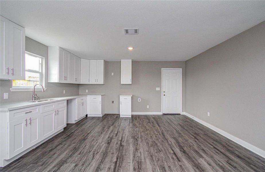 Bright kitchen featuring white cabinetry, generous counter space, and a window above the sink.