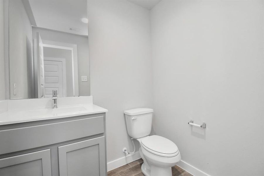 The half bathroom, conveniently situated on the 1st floor, is adorned with contemporary finishes. Light cabinets paired with a light countertop, custom wall paint, and sleek faucet combine to create a bright and inviting space. Sample photo of completed home with similar floor plan. As-built interior colors and selections may vary.