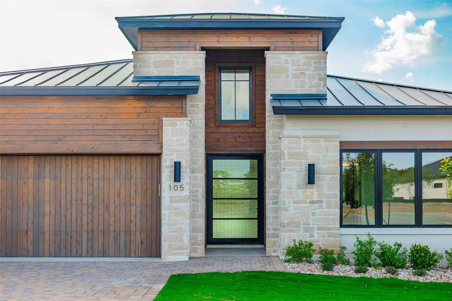 Doorway to property featuring a standing seam roof, stone siding, and a metal roof