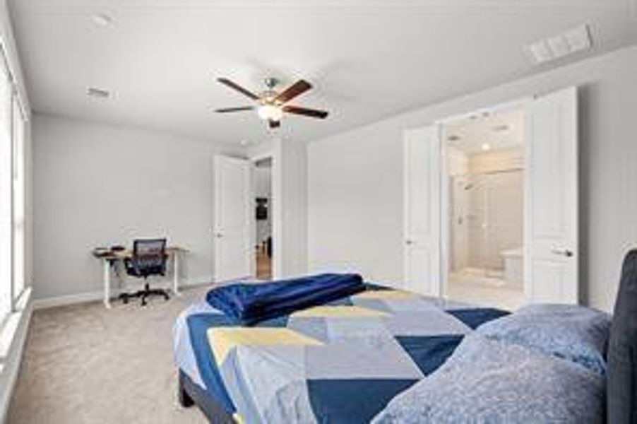 Carpeted bedroom featuring ceiling fan and ensuite bathroom