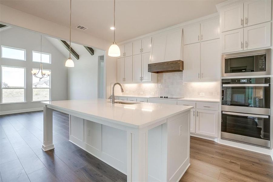 Kitchen with appliances with stainless steel finishes, white cabinetry, sink, and an island with sink