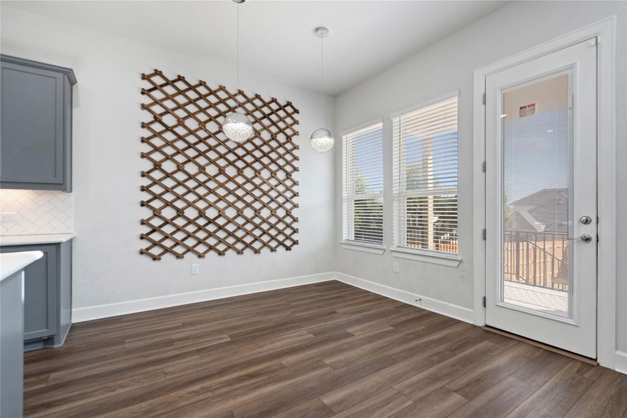 Rich wood-look flooring and multiple windows enhance this welcoming dining area next to the deck access.