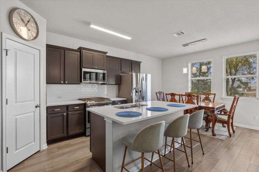Streamlined cabinetry and a central island ground this open culinary space with warm flooring.