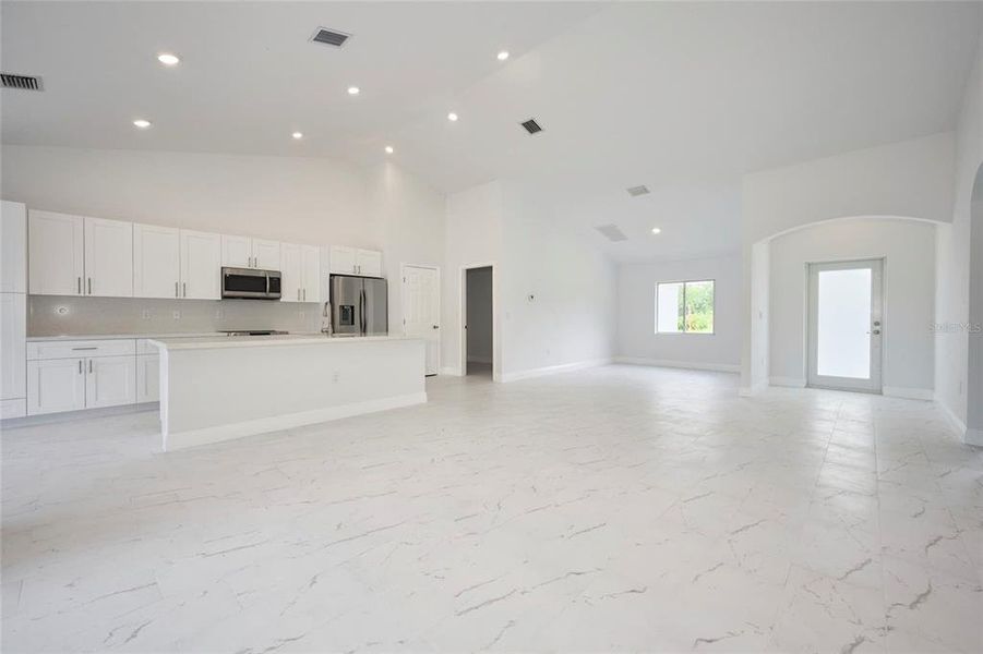 Reverse view of kitchen, front entrance and dining area/flex space.  Open door on the left leads into laundry room and out to garage.