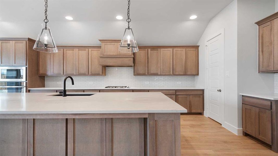 Kitchen featuring appliances with stainless steel finishes, sink, a center island with sink, and light hardwood / wood-style flooring