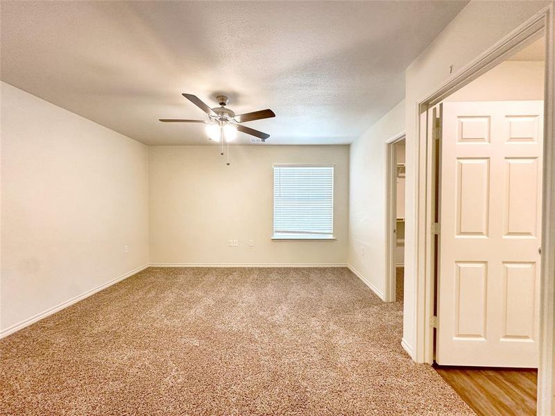 Unfurnished room with a textured ceiling, ceiling fan, and light colored carpet