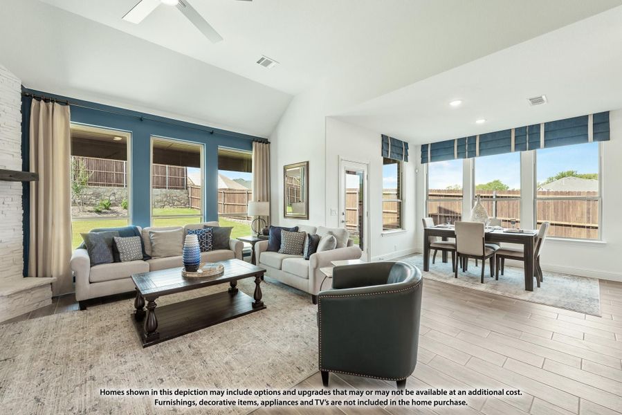Open living room with vaulted ceiling, large windows, two sofas, and adjacent dining area with hardwood-style floors. Open living room with vaulted ceiling, large windows, two sofas, and adjacent dining area with hardwood-style floors.