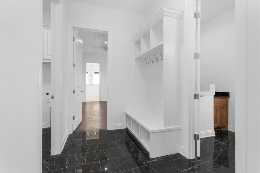 This well-appointed mudroom features built-in storage with hooks and cubbies, offering a stylish and functional landing zone just off the home’s secondary entry. Utility room and pet washing station on either side. This well-appointed mudroom features built-in storage with hooks and cubbies, offering a stylish and functional landing zone just off the home’s secondary entry. Utility room and pet washing station on either side.