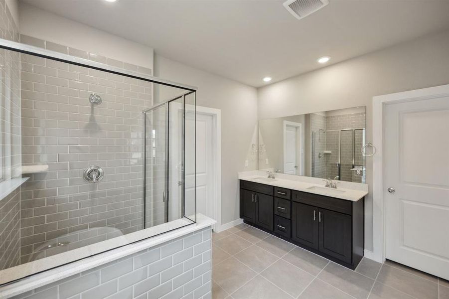 Spa like primary bathroom featuring a walk-in shower and dual sinks