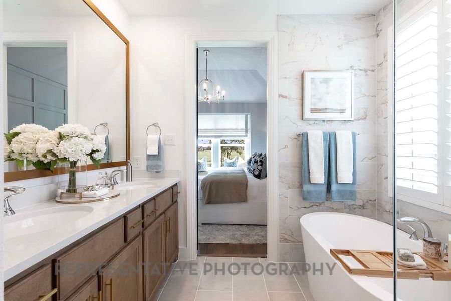 Ensuite bathroom featuring plenty of natural light, a freestanding bath, double vanity, and tile patterned flooring Ensuite bathroom featuring plenty of natural light, a freestanding bath, double vanity, and tile patterned flooring