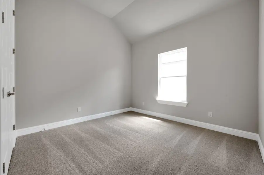 Carpeted empty room with lofted ceiling and baseboards
