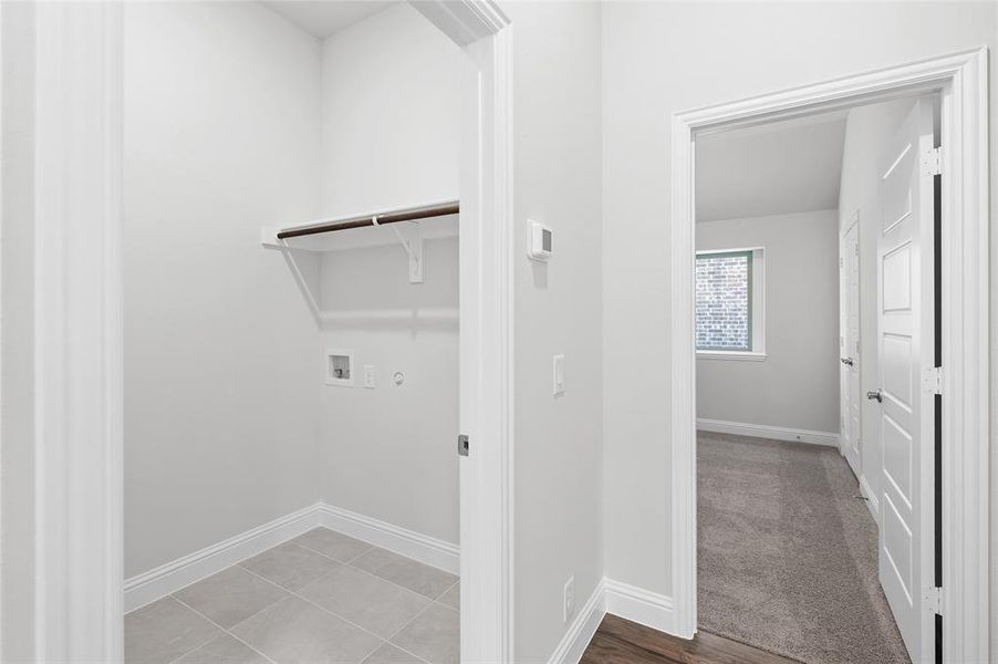 Washroom with hookup for a washing machine, hookup for a gas dryer, and light tile patterned floors