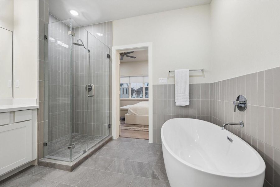Primary bath, porcelain tiles, chrome finishes, large soaking sub, quartz counters, frameless glass shower. - Photo is of model at 6340, finishes are similar. Primary bath, porcelain tiles, chrome finishes, large soaking sub, quartz counters, frameless glass shower. - Photo is of model at 6340, finishes are similar.