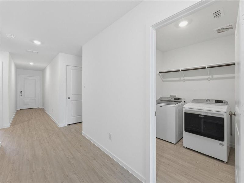 Dedicated laundry area featuring a washer, dryer, and overhead shelving