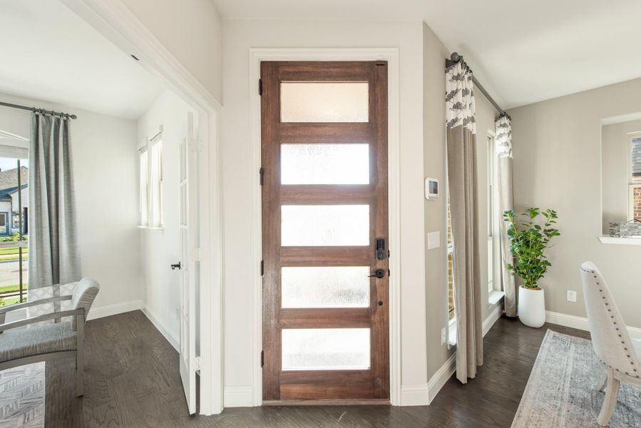 Wood front door with five glass panels in a home entryway with dark hardwood floors