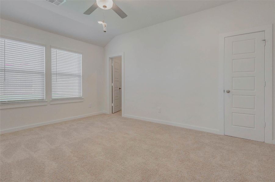 The spacious primary bedroom offers the perfect retreat with soft carpet underfoot, a ceiling fan overhead, and twin windows that flood the space with light. Neutral walls and trim make decorating easy, while the en suite access adds convenience and privacy for homeowners looking to relax and recharge.