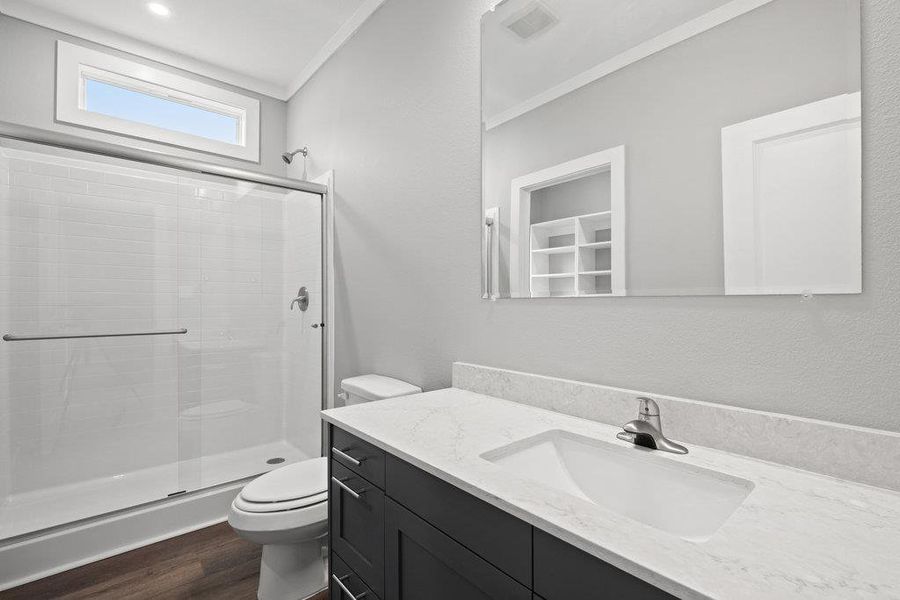 Full bathroom with a stall shower, vanity, dark wood finished floors, and ornamental molding