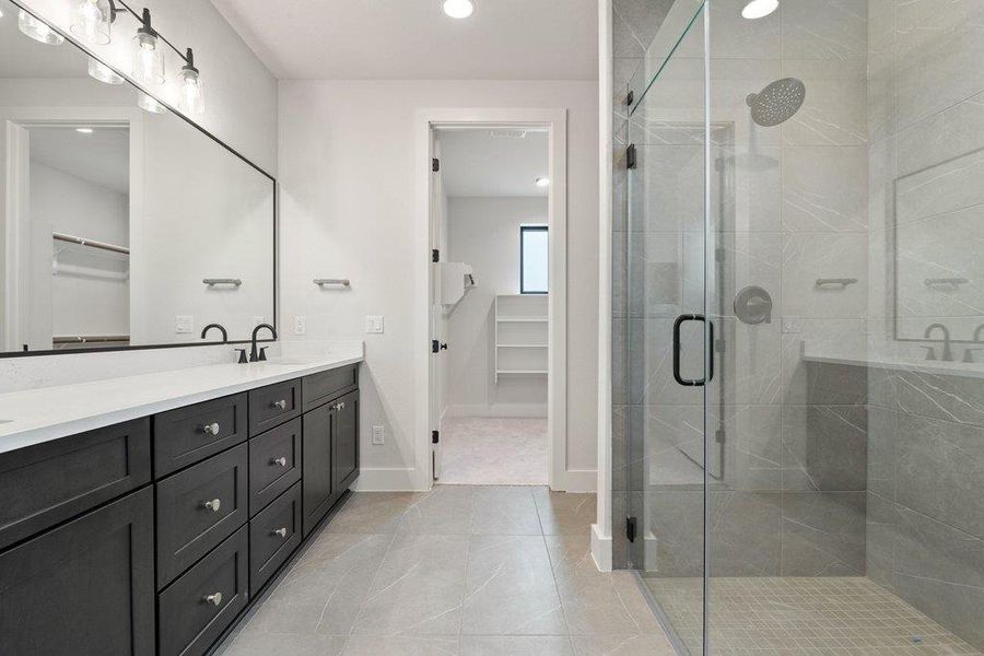 Bathroom featuring a spacious closet, a stall shower, double vanity, light tile patterned floors, and recessed lighting