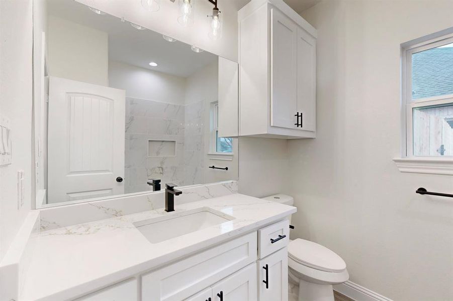 Bathroom with plenty of natural light, toilet, vanity, and a tile shower