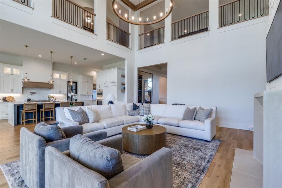 Living area with a chandelier, light wood finished floors, and a high ceiling Living area with a chandelier, light wood finished floors, and a high ceiling