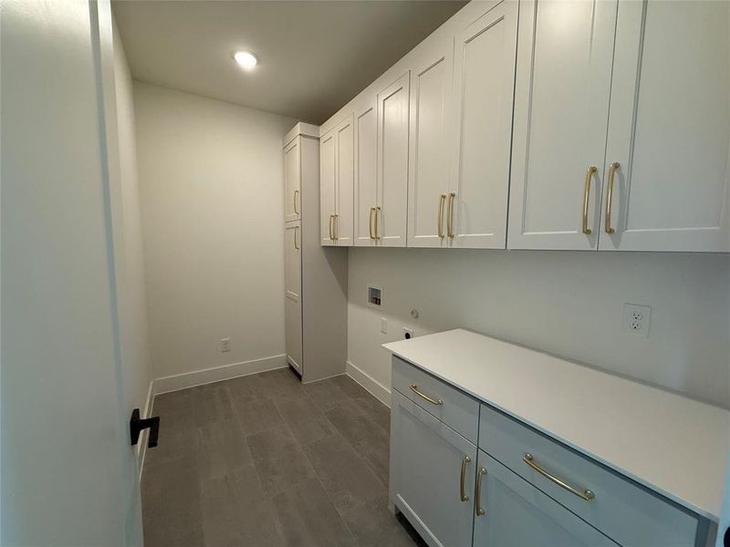 Clothes washing area with cabinets, hookup for a washing machine, and hookup for an electric dryer