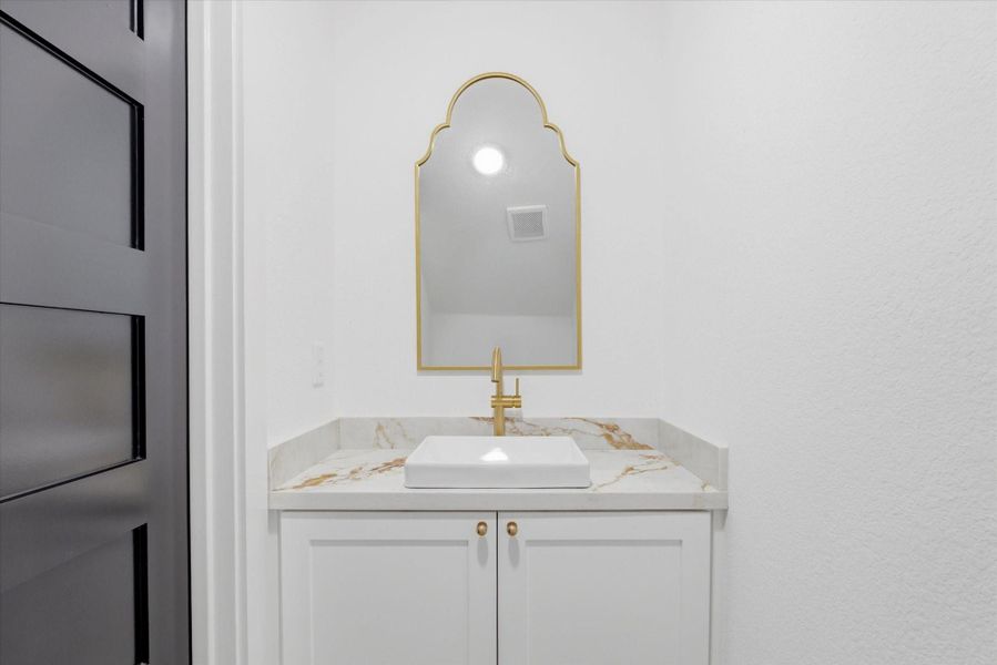 Tucked underneath the stairs is a chic half-bath featuring hexagon tile flooring, a modern floating vanity, and a decorative mirror, offering a sophisticated and functional touch for guests.