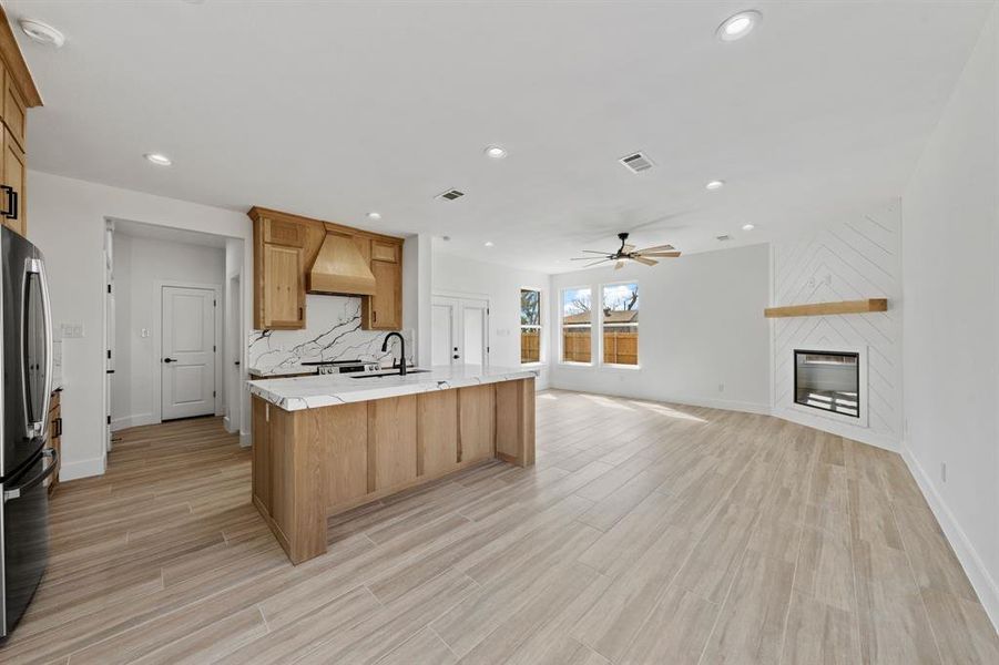 Kitchen with a large fireplace, a sink, visible vents, open floor plan, and light countertops