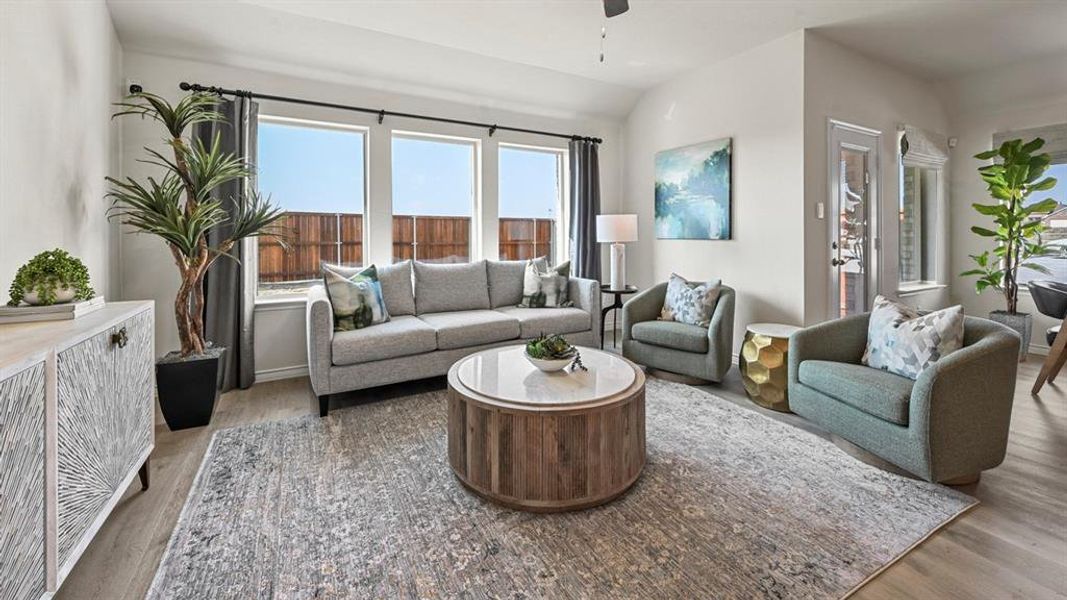 Living area with light wood-style flooring, healthy amount of natural light, lofted ceiling, and a ceiling fan