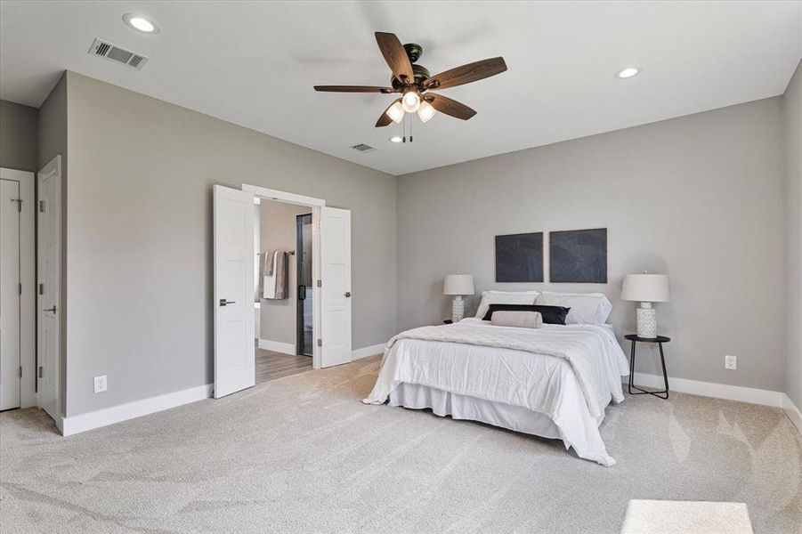 Bedroom with light colored carpet, connected bathroom, and ceiling fan