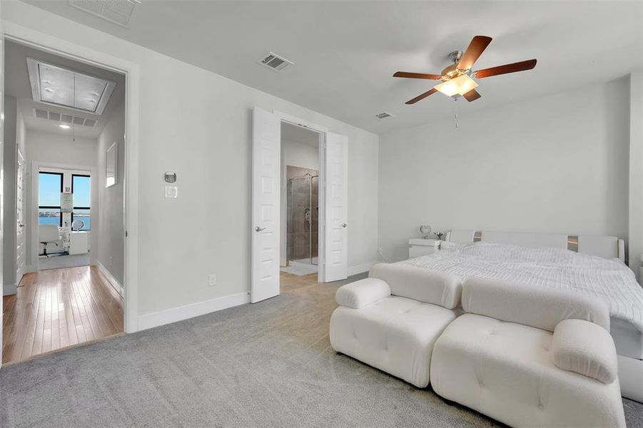 Bedroom with light hardwood / wood-style floors, ensuite bath, and ceiling fan