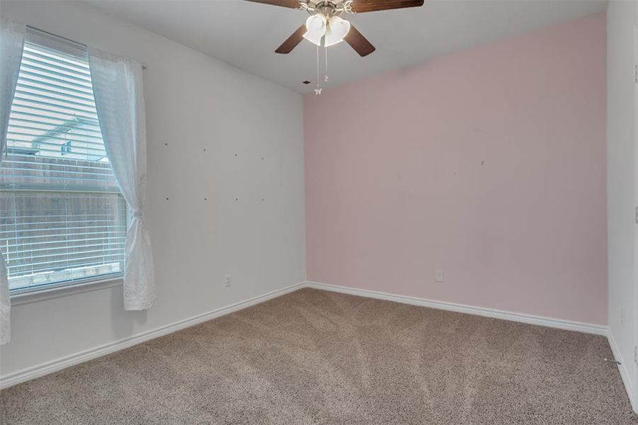 Carpeted empty room with plenty of natural light and ceiling fan