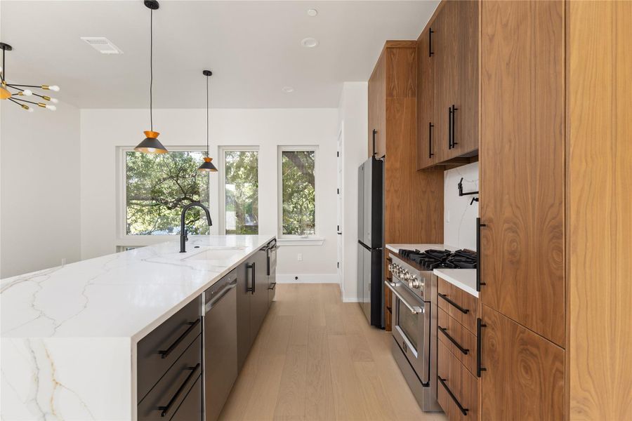 Rich wood cabinetry contrasts beautifully with a waterfall-edge stone island and modern stainless appliances.