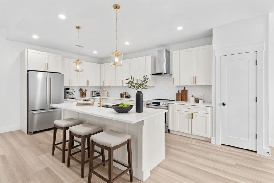Virtually staged Kitchen with a kitchen breakfast bar, stainless steel appliances, white cabinetry, an island with sink, and recessed lighting