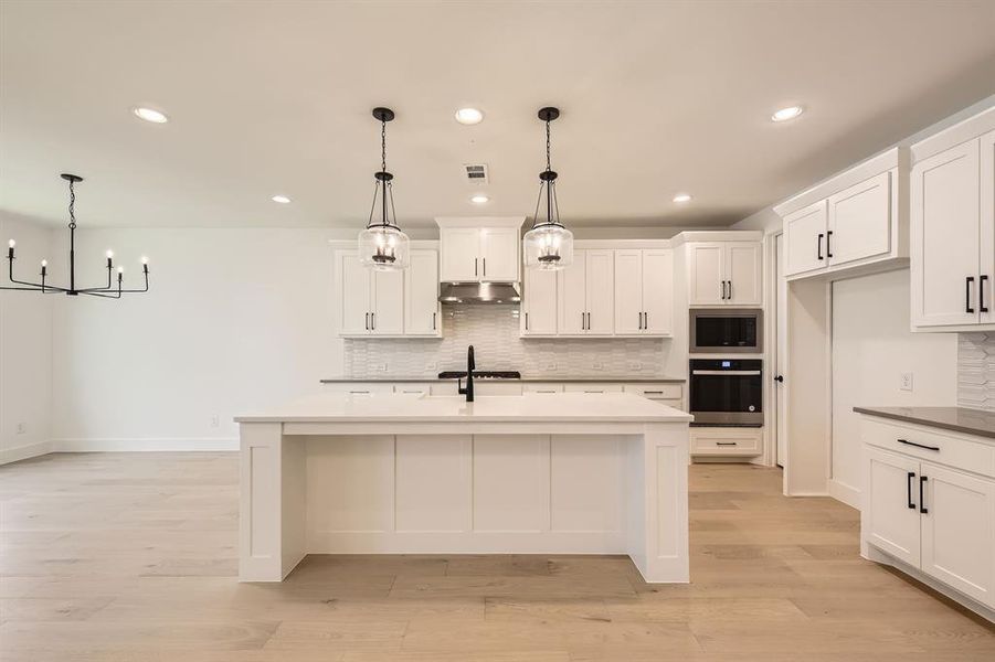 Kitchen with oven, under cabinet range hood, stainless steel microwave, tasteful backsplash, and recessed lighting