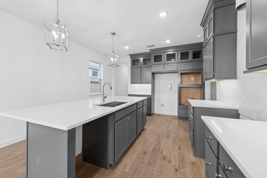 Stylish kitchen with grey stacked cabinets and quartz counters