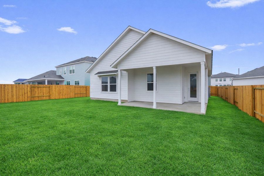 A well-maintained lawn extends from the home's rear patio, enclosed by a classic wood privacy fence.