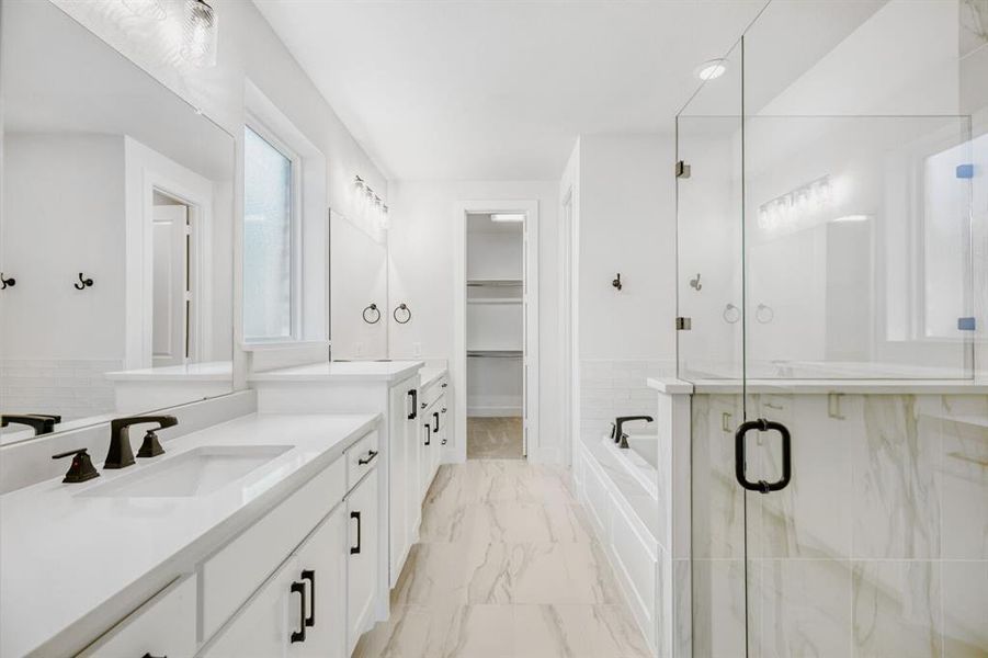 Bright bathroom featuring dual vanities with integrated sinks, white countertops, and matte black fixtures