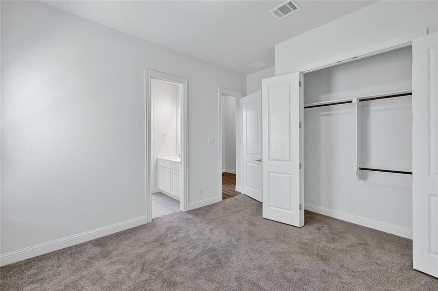 Unfurnished bedroom with light colored carpet, a closet, and ensuite bath