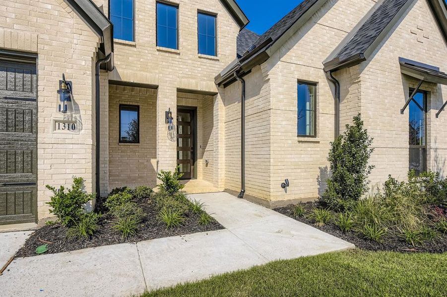 Entrance to property featuring brick siding and a shingled roof