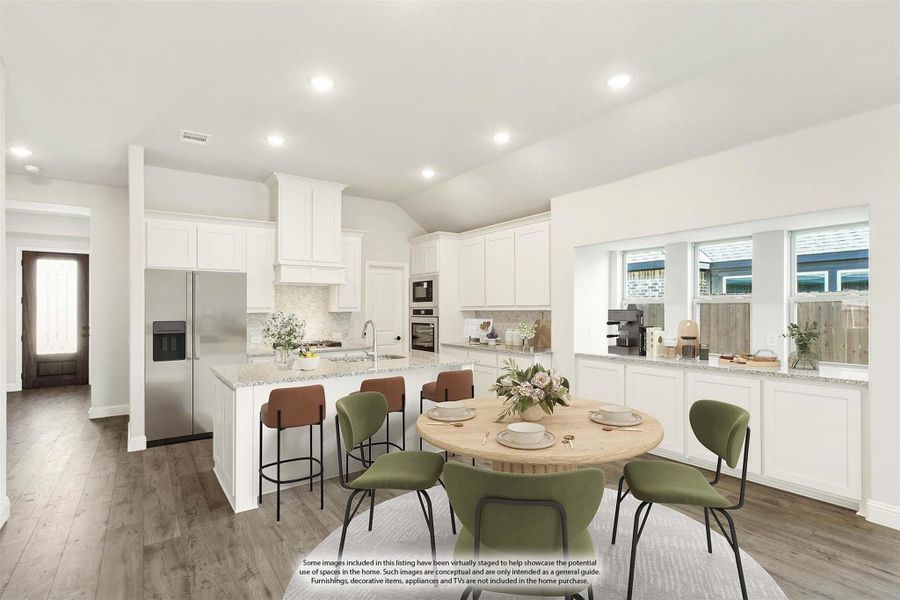 Open-concept kitchen and dining area with white cabinets, granite island, stainless appliances, and round dining table with green chairs