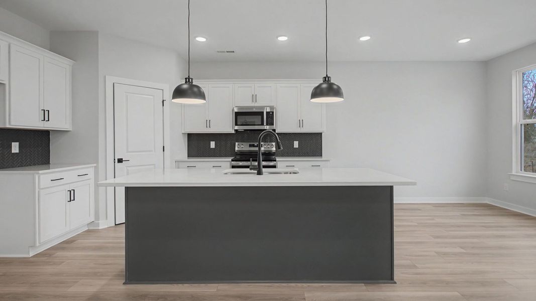 Kitchen with white cabinets and quartz countertops, tile accent backsplash, and pendant lighting
