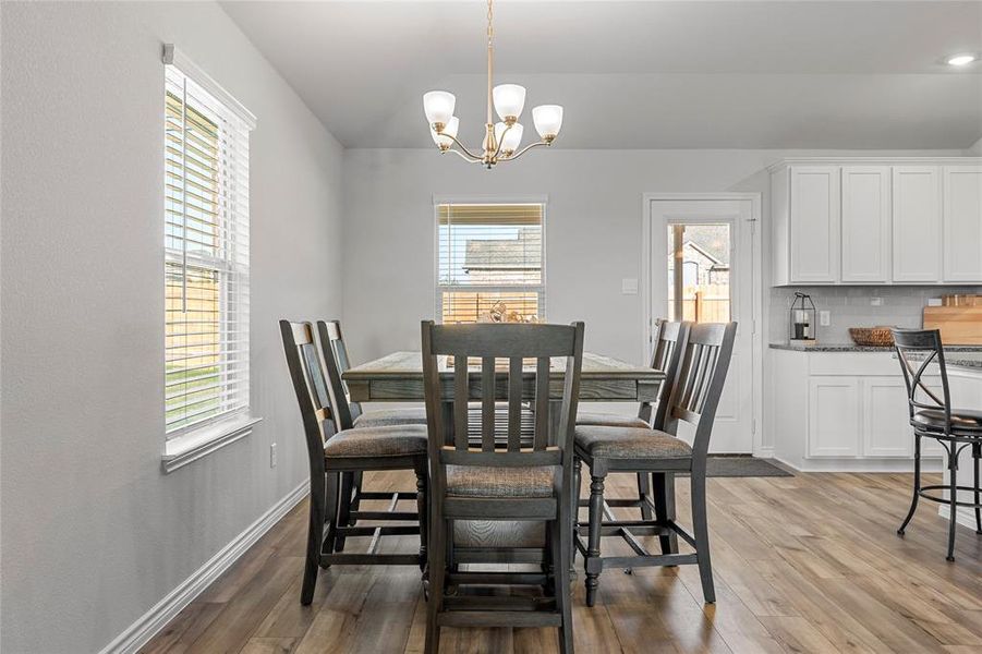 Dining room with vaulted ceiling, healthy amount of natural light, light wood finished floors, and a chandelier