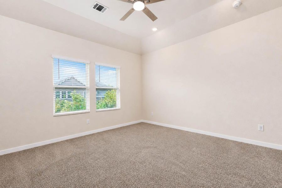Spacious primary bedroom offers a calm, comfortable retreat with plush carpeting, two windows providing natural light, a tray ceiling, recessed lighting, and a contemporary ceiling fan. The generous room dimensions allow plenty of flexibility for a complete bedroom suite, seating area, or additional furnishings. Spacious primary bedroom offers a calm, comfortable retreat with plush carpeting, two windows providing natural light, a tray ceiling, recessed lighting, and a contemporary ceiling fan. The generous room dimensions allow plenty of flexibility for a complete bedroom suite, seating area, or additional furnishings.