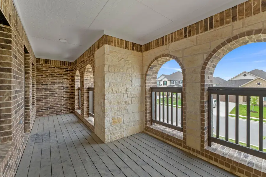 Balcony featuring arched openings with stone and brick accents, wood-finish flooring, and black railings